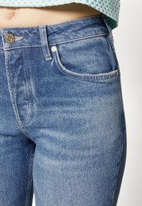 Modré džíny s vysokým pasem nabízející klasický pětipocketový design, kovový knoflíkový zip a jemné zesvětlení pro strukturu.