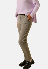 Pantalons taillés gris clair à coupe slim, présentant une texture lisse et des poches latérales, associés à des mocassins noirs et un pull lavande.