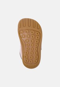 Suela de zapato de goma con superficie texturizada, que presenta patrones de agarre circulares. Color: marrón claro. Marca: Camper, indicada en el talón.