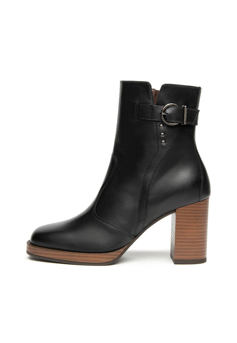 Schwarze Leder-Ankle-Boots mit Holzblockabsatz, seitlichem Schnallenriemen und dekorativen Metallnieten an der Außenseite.