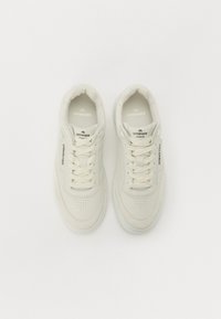 Hvite lær sneakers med perforerte detaljer, flate lisser og polstret krage. Har logo på tungen og siden. Teksturert såle.