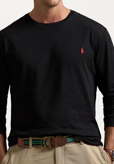 Zwarte long-sleeve t-shirt met ronde hals en klein rood polo-logo. Draag het met beige broek en een meerkleurige gestreepte riem met een bruine gesp.