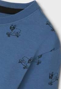Blå sweatshirt med grafisk tryk af en sort skateboarderhund, ribbet rund halsudskæring og struktureret stof. Har et gentagende legesygt hundemønster.