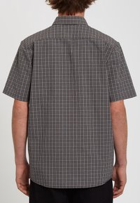 Chemise à manches courtes à motif à carreaux noir et blanc, dotée d'un col ouvert et d'un empiècement arrière, avec une coupe décontractée et une texture lisse.