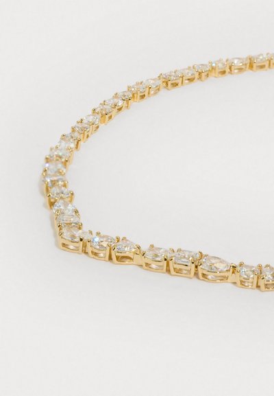 Collier en ton doré avec des pierres claires taillées en ovales, montées dans un design simple et entrelacé. Texture lisse avec une finition brillante.