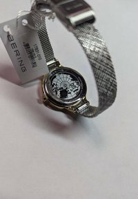 Bering watch with a round silver mesh band. Black, patterned dial features a world map design. Includes a price tag attached.