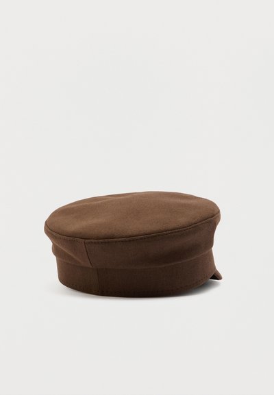 Καφέ βαμβακερό καπέλο με επίπεδη κορυφή και μικρό, κεκλιμένο γείσο, απεικονίζεται πάνω σε απλό γκρι ανοιχτό φόντο.