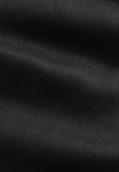 Hladká černá látka s jemnými záhyby a jemnou tkanou texturou viditelnou pod měkkým osvětlením.