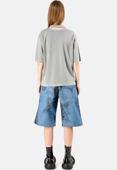 Gray short-sleeve shirt, relaxed fit, paired with blue denim shorts featuring a faded pattern and black accents, worn with black ankle boots.