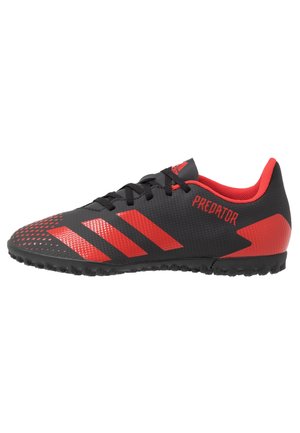Sort og rød Adidas Predator fodboldstøvle med tekstureret sål, røde striber og sorte snørebånd, designet til spil på kunstgræs.