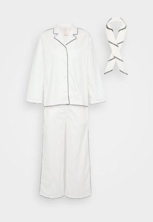Hvid bomulds pyjamas sæt med sort piping. Indeholder en skjorte med knap-lukning og lange ærmer samt bukser med brede ben, ledsaget af et matchende tørklæde.