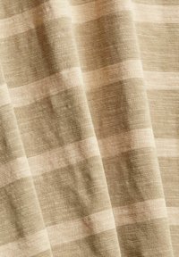 Tissu beige doux avec des rayures horizontales plus claires, présentant un motif de tricot texturé et de légers plis.