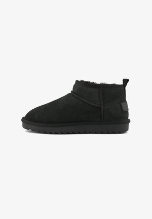 Stivaletto alla caviglia in suede nero, slip-on, con punta rotonda, fodera morbida, linguetta sul tallone e suola in gomma rigata.