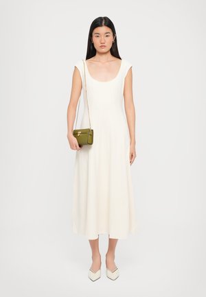 White midi dress with a scoop neckline and cap sleeves, paired with a small green handbag and white pointed-toe shoes. Smooth texture.