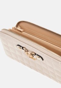 Beige gesteppte Geldbörse mit goldenem Reißverschluss und Schnalle, geöffnet, um mehrere Fächer und Kartensteckplätze im Inneren zu zeigen.