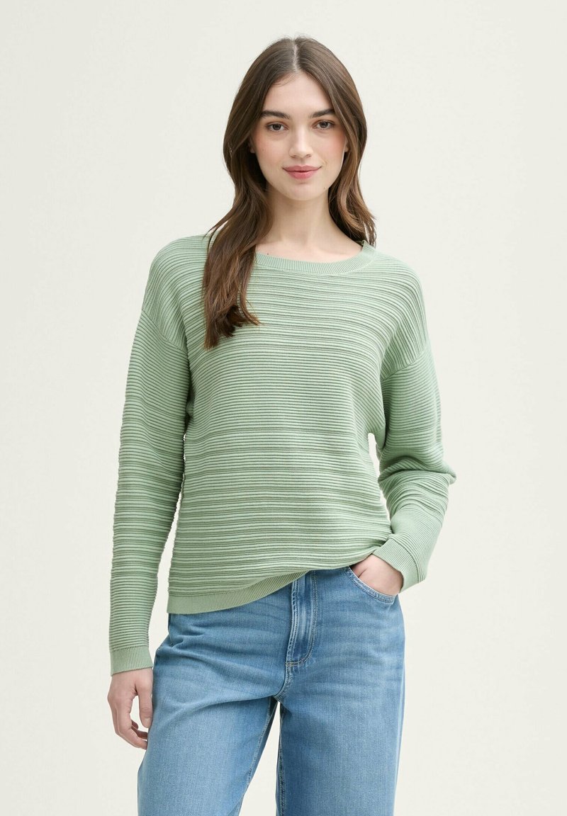 Suéter de rayas verde claro con escote redondo y mangas largas, combinado con jeans azules. La textura presenta un canalé horizontal.