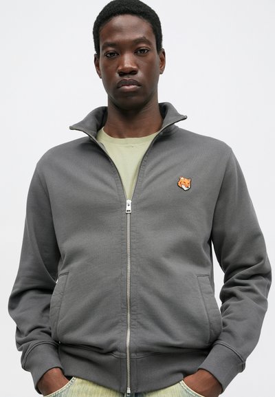 Gray zip-up jacket made of soft fabric, features a high collar, two side pockets, and a small orange fox embroidery on the chest.
