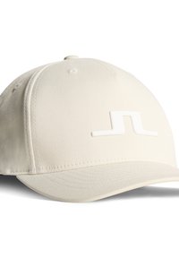 Beige keps i texturerad tyg, med en styv skärm och en vit logotyp på framsidan. Sex ventilationshål är synliga på toppen.