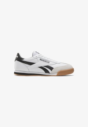 Sneaker bianca con dettagli neri, punta in suede, finitura in pelle liscia e suola in gomma. Include lacci e linguetta con marchio.
