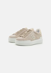 Beežist suede'ist tennisjalad valgete kummist taldadega, ümarate varvastega ja tekstuursete detailidega. Omavad kerget logo ja seotud disaini.