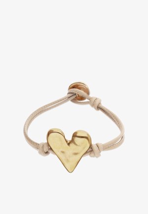 Bracelet en cuir beige avec des extrémités nouées, orné d'un charm en forme de cœur brillant en or au centre et d'un fermoir rond en or.