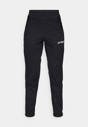 Black athletic pants with a smooth fabric, featuring a fitted design, zippered pockets, and a textured lower leg. Logo printed on the front.