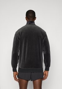 Γκρι βελουτέ ζακέτα με ψηλό γιακά, ριμπ μανσέτες και στρίφωμα. Λείο υλικό και εφαρμοστή γραμμή, που αναδεικνύει έναν μινιμαλιστικό στυλ.