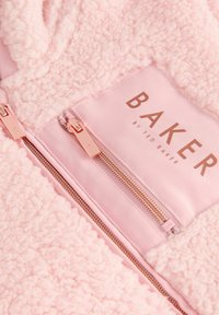 Morbido tessuto sherpa rosa con due cerniere in oro rosa e un'etichetta con la scritta "BAKER by Ted Baker" sul pannello in tessuto liscio.