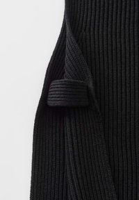 Schwarzer gerippter Strickstoff mit einem umgeschlagenen Bündchen, vor einem weißen Hintergrund gezeigt.