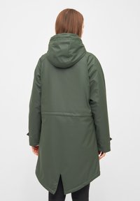 Zelená nepromokavá parka s úzkým pasem, kapucí a výřezem na zádech. Vyrobena z hladkého, odolného materiálu. Dlouhé rukávy.