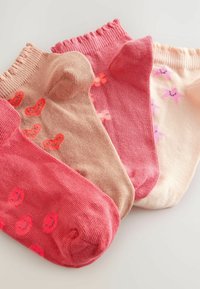 Set med tre par ankelsockor i olika nyanser av rosa och persika, med mönster av hjärtan och stjärnor; ribbade toppar och mjuk textur.