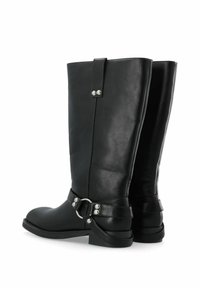 Las botas de cuero negro hasta la rodilla presentan una punta redondeada, una correa con herrajes plateados y una textura suave. El diseño incluye un acento de hebilla lateral.