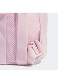 Rosa ryggsäck med en texturerad mesh-kropp, släta accenter, tjocka remmar och ett sidspärr för säker stängning.