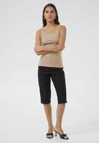 Top fără mâneci, în dungi bej și maro, combinat cu pantaloni scurți negri. Topul are bretele late și un guler rotund, în timp ce pantalonii au o croială relaxată și o ușoară strălucire.