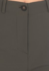 Pantaloni verde scuro con chiusura anteriore a bottoni, fronte piatto e cuciture pulite, realizzati in un tessuto liscio e texturizzato.