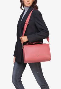 Roze leren handtas met een strakke rechthoekige vorm. Bevat gouden hardware, een afneembare schouderriem en dubbele handvatten aan de bovenkant.