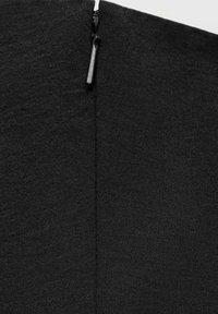 Crni tekstilni odjevni predmet s vidljivim patentnim zatvaračem uz šav, sa glatkom teksturom i elegantnim dizajnom. Minimalni detalji šivanja.