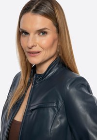 Dunkelblaue Lederjacke mit Stehkragen, groen Reißverschluss und einer Brusttasche. Glatte Textur mit minimalen Nähdetails.