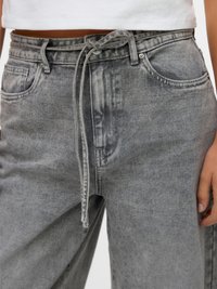 Grå denim bukser med avslappet passform, med snøring i midjen og frontlommer. Stoffet har en slitt tekstur med subtil fading.