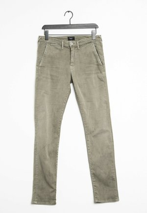 Olivgrüne, schlanke Herrenhose mit Knopf- und Reißverschluss, Gürtelschlaufen und Vordertaschen, die an einem schwarzen Kleiderbügel hängt.