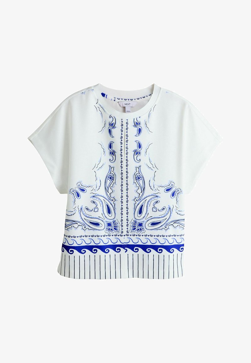 Blouse blanche à manches courtes avec motifs cachemire bleus et floraux abstraits, encolure ronde et accents de rayures verticales le long de l'ourlet.