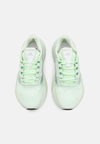 Scarpe da atletica verde chiaro con tomaia in mesh, collare imbottito e punta rotonda. Presentano una chiusura con lacci e dettagli testurizzati sui lati.