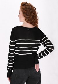 Maglione a righe bianco e nero con una vestibilità ampia, polsini a coste e scollatura a barca; leggero, texture a maglia, vista da dietro.