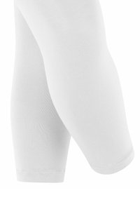 Witte knielange leggings van rekbaar, geribbeld stof met een gladde textuur en een elastische tailleband, geschikt voor sportkleding of als laagjes.