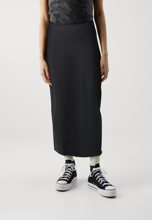 Black, mid-length skirt made from a smooth fabric. Paired with black high-top sneakers and cream-colored socks.