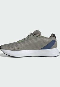 Scarpa sportiva leggera con tomaia in mesh grigio, superficie testurizzata, accento verde e suola bianca ammortizzata. Presenta un dettaglio nero sul tallone.