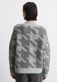 Gray patterned sweater with a ribbed neckline and hem, featuring a textured knit and a geometric design in darker gray tones.