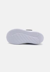 Baskets noires avec une semelle extérieure en caoutchouc blanc texturé, présentant un motif en diamants et des rainures profondes pour une meilleure adhérence. Design simple et fonctionnel.