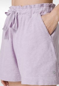 Lavendelfärgade frottéshorts med elastisk midja och dragsko. Har sidofickor och en liten logga i nederkanten.