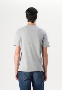 Tricou gri din bumbac cu mâneci scurte, decolteu rotund și o textură fină, asortat cu blugi albaștri din denim cu un croi clasic.